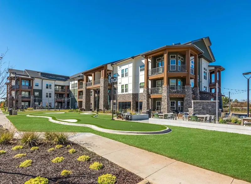 The Fitzroy Grove apartments in Rogers, Arkansas, with stone columns, balconies and a courtyard putting green